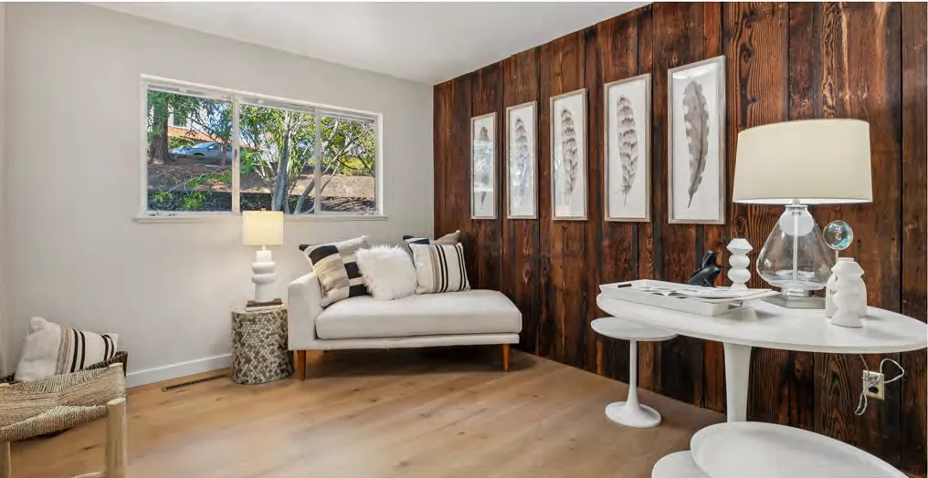 A staged sitting room with an original wood plank wall retained as a feature